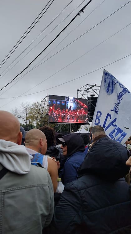 Desde la fila se puede observar una pantalla que muestra el interior del Polideportivo Gatica, donde está la Capilla Ardiente