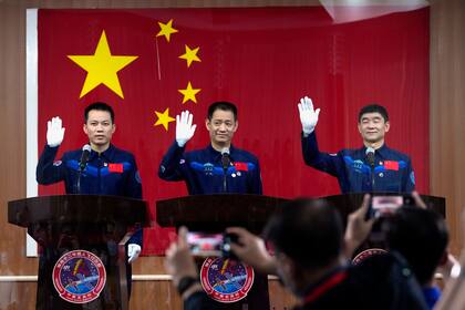 Desde la izquierda, los astronautas chinos Tang Hongbo, Nie Haisheng y Liu Boming saludan a los reporteros un día antes de viajar hacia la estación espacial china Tianhe o Armonía Celestial, el 16 de junio de 2021 en Jiuquan, China. (AP Foto/Ng Han Guan)