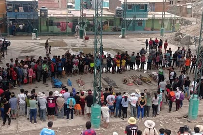 Los residentes en Camaná, Perú, alrededor de los cuerpos de las personas que murieron en los recientes deslizamientos de tierra, el lunes 6 de febrero de 2023.  (AP Photo/Ever Chambi)