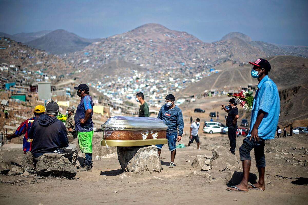 Desolación. Un grupo de hombres aguarda junto al féretro de una víctima de Covid-19, en el cementerio Esperanza, al sur de Lima, en mayo de este año