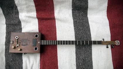 Detalle de la guitarra de tres cuerdas hecha a partir de una caja de cigarros