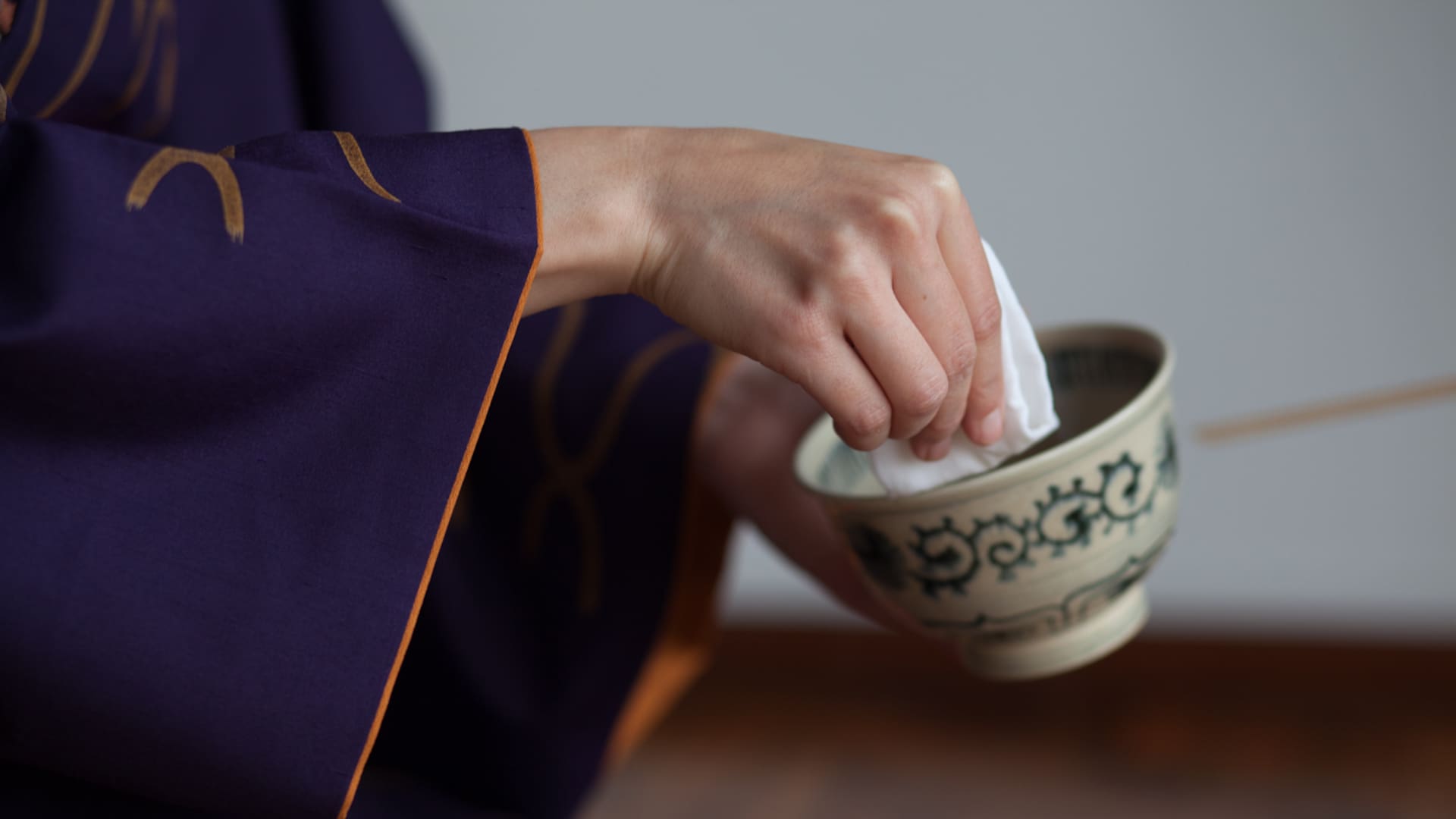 Detalle de manos limpiando cuenco en una tradicional ceremonia del té japonesa.