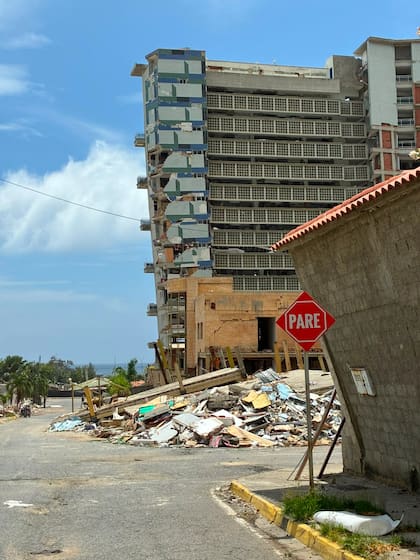 Detrás del cartel de pare, un complejo habitacional luce a punto de desplomarse