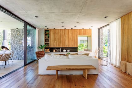 Banco de madera maciza (carpintero Pablo Amadeo). Piso de roble labrado (Patagonia Flooring). La chimenea de hierro se diseñó integrada al frente y forma una L con los estantes.