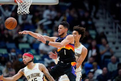 Devin Booker (1), de los Suns de Phoenix, manda pase para quitarse presión de Jaxson Hayes y José Alvarado, en la primera mitad del juego de la NBA en Nueva Orleans, el martes 4 de enero de 2022. (AP Foto/Gerald Herbert)