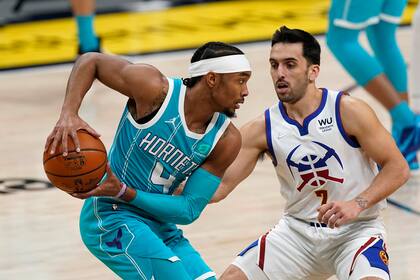 Devonte' Graham, de Charlotte Hornets, protege la pelota ante un experto ladrón, Facundo Campazzo, de Denver Nuggets.