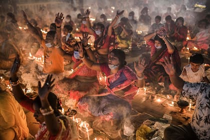 Devotos hindúes se sientan en el suelo entre velas encendidas, mientras realizan rituales frente a Shri Shri Lokanath Brahmachar Ashram durante el festival hindú Rakher Upobash en Bangladesh