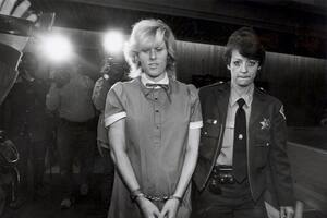 Diane Downs, esposada y escoltada por una agente, durante una de sus apariciones judiciales tras ser condenada por el asesinato de su hija y el intento de homicidio de sus otros dos hijos en Oregon