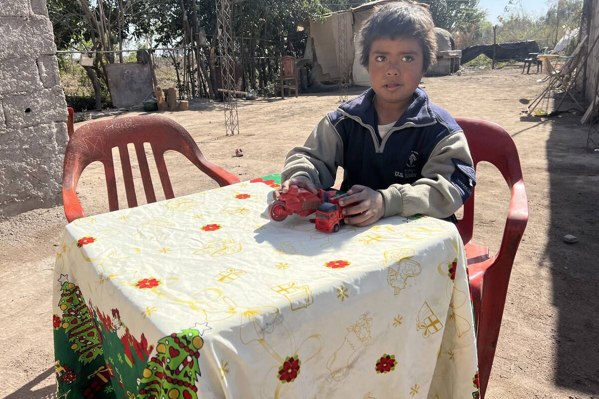 Diego Riveros juega con sus juguetes preferidos en el patio de su casa; de fondo se puede ver el horno y la cocina precaria