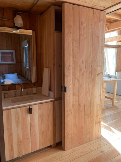 Diseñaron una puerta que funciona a modo de pared, que divide el ambiente principal donde está el living y la cocina del cuarto con su baño en suite.