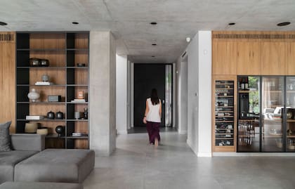 Diseños de Bussoli, el mueble de guardado con puertas enchapadas en madera petiribí (Slott Furniture) en continuidad con una biblioteca laqueada en gris grafito.