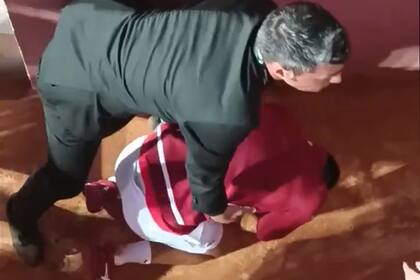 Djokovic se apoya en el piso, sostenido por una persona de la seguridad del torneo de Roma, luego de recibir un botellazo