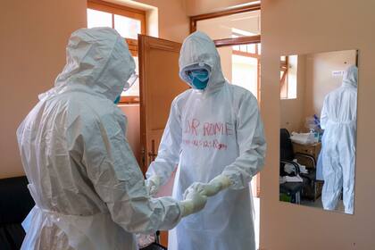 Doctores con equipo de protección oran antes de visitar a un paciente que estuvo en contacto con una víctima de ébola, en el pabellón de aislamiento del Hospital Regional de Remisión de Entebbe, el 20 de octubre de 2022, en Entebbe, Uganda. (AP Foto/Hajarah Nalwadda, archivo)