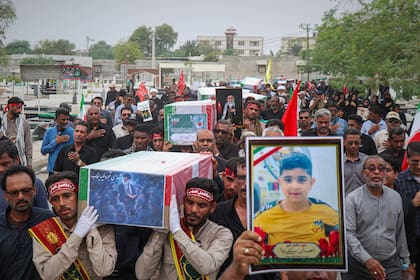 Dolientes cargan ataúdes de víctimas recién identificadas con pruebas de ADN en un funeral en Minab, Irán