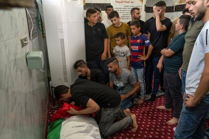 Dolientes miran por última vez el cadáver del palestino Salah Sawafta, de 58 años, que murió baleado cuando volvía de orar este mes, durante una redada matutina del ejército israelí, en su funeral en una mezquita, en Tubas, Cisjordania, el viernes 19 de agosto de 2022. (AP Foto/Nasser Nasser)