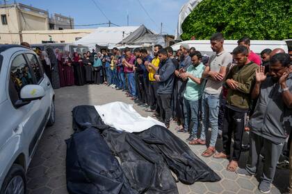 Dolientes rezan sobre los cuerpos de palestinos fallecidos en un ataque aéreo israelí en Nuseirat, en el hospital de Al Aqsa en Deir al Balah, en la Franja de Gaza, el sábado 27 de abril de 2024. (AP Foto/Abdel Kareem Hana)