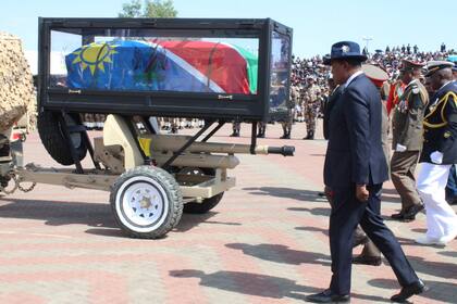 Dolientes siguen el ataúd envuelto en una bandera del fallecido presidente de Namibia, Hage Geingob, durante su funeral en Windhoek, Namibia, el domingo 25 de febrero de 2023. (AP Foto/Esther Mbathera)