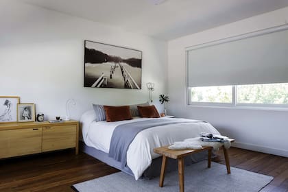 Dormitorio con piso de incienso y alfombra de lana (Mihran). Cama con mantas combinadas (Du Sud) y cómoda de madera (Encaja Muebles).
