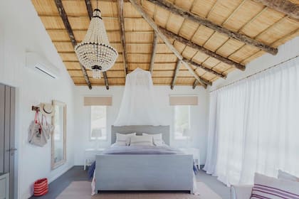 En el dormitorio principal, el color natural de las fibras contrasta con el blanco etéreo elegido para las paredes y las cortinas.