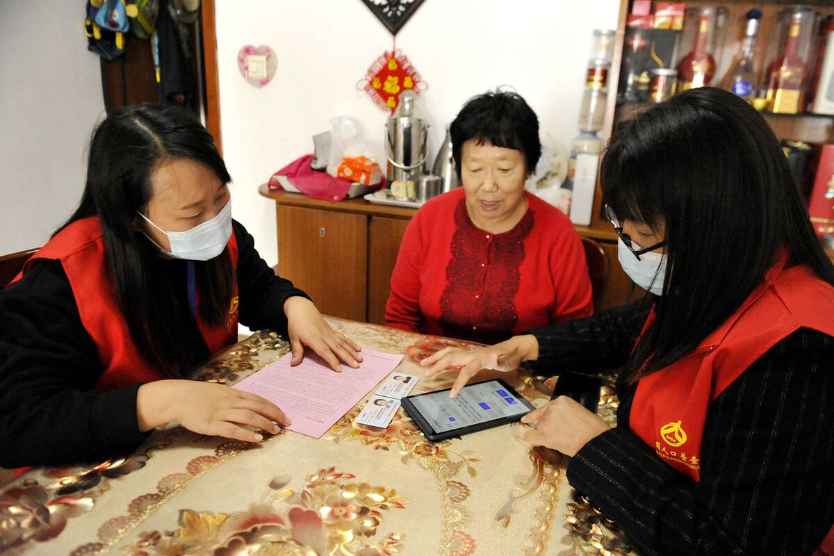 Dos agentes del censo nacional cargan los datos de una mujer en la provincia de Shandong, en el este de China