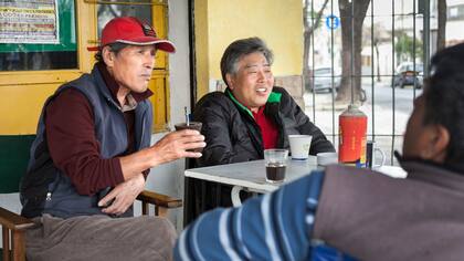 Dos amigos comparten un cortado, junto a carteles en coreano, sobre Carabobo