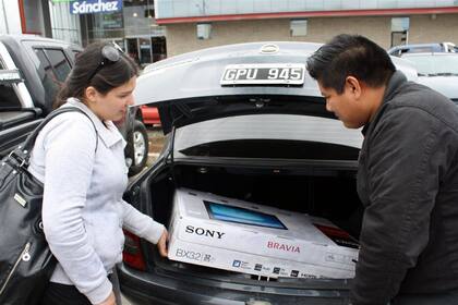 Dos argentinos compran un LCD en Punta Arenas, Chile. La escasez de modelos de cubiertas para autos de lujo es un problema que afecta a gomerías de todo el país.