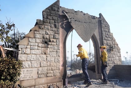 Dos bomberos examinan los daños en la iglesia episcopal San Marcos después de que fue destruida por el incendio Eaton, el viernes 10 de enero de 2025, en Altadena, California. (AP Foto/Chris Pizzello)