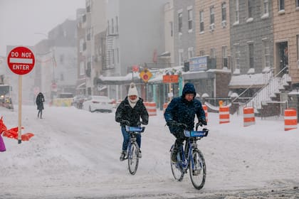 Dos ciclistas circulan por Brooklyn durante una tormenta de nieve, el 29 de enero de 2022.