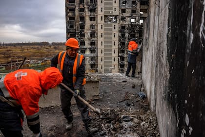Dos colaboradores realizan trabajos de limpieza en un edificio en las afueras de Kharkiv