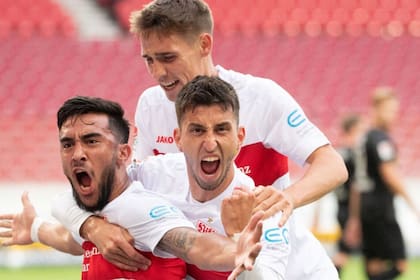 Dos compañeros de Stuttgart abrazan a Nicolás González, autor de 14 goles en la campaña del ascenso a la Bundesliga