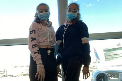 Dos de las chicas posan después de haber pasado los controles de seguridad y sanitarios, horas antes de subir al avión de Aerolíneas Argentinas