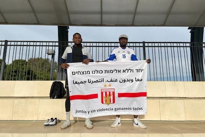 Dos de los integrantes del plantel de Estudiantes de Tel Aviv y un mensaje que simboliza la idiosincrasia del equipo.