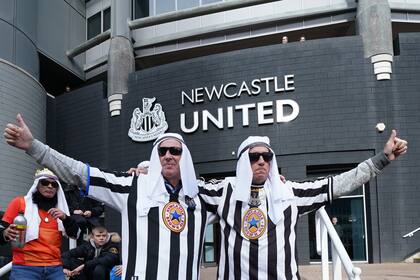 Dos hinchas de Newcastle posan con turbantes antes de un partido con Tottenham en Londres el 17 de octubre del 2021. El club acaba de ser adquirido por intereses árabes. (AP Photo/Jon Super)