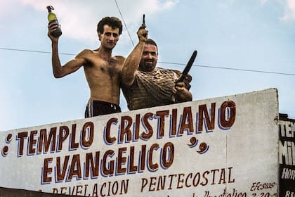 Dos hombres en el techo de un templo religioso muestran armas de fuego y una molotov para defenderse de eventuales saqueos, en el conurbano bonaerense el 21 de diciembre de 2001