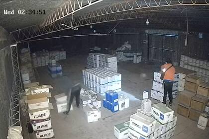 Dos ladrones metidos en un galpón de un campo robando insumos agropecuarios