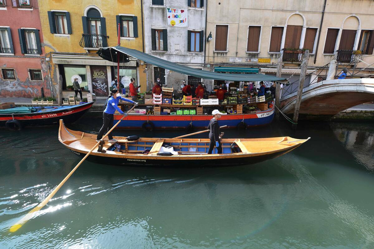 Dos mujeres, con barbijo, se ocupan del mantenimiento de los canales de Venecia en medio de la pandemia por coronavirus