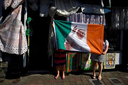 Dos mujeres de una tienda de mercería sostienen una bandera de Irlanda con la imagen del Papa Francisco en Louth