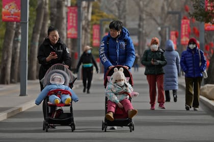 Dos mujeres pasean con niños por un parque en Beijing, China, el 19 de enero de 2023. (AP Foto/Andy Wong)
