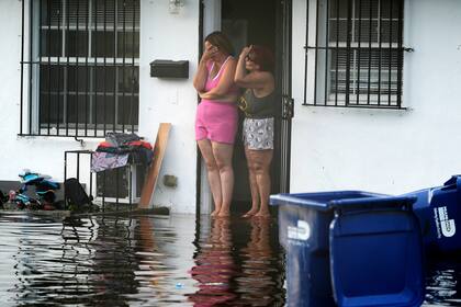Dos mujeres reaccionan al ver su calle inundada, el jueves 13 de junio de 2024, en North Miami, Florida. (AP Foto/Marta Lavandier)