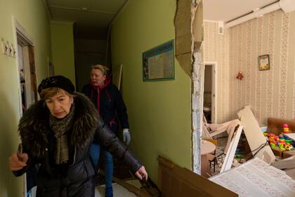 Dos mujeres recorren el interior de una escuela dañada, junto a otros edificios residenciales, en un bombardeo, en Kiev, Ucrania, el 18 de marzo de 2022. (AP Foto/Rodrigo Abd)