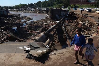 Dos niñas caminan en un camino dañado, el jueves 14 de abril de 2022, en Durban, Sudáfrica. (AP Foto/Str)