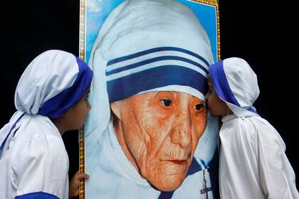 Dos niñas vestidas como Misioneras de la Caridad besan un retrato de la Madre Teresa de Calcuta durante una ceremonia en su honor en Bhopal, India
