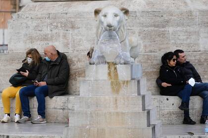 Dos parejas descansan junto a la Fuente de los Leones en la Piazza del Popolo, el miércoles 5 de enero de 2022, en Roma. (AP Foto/Gregorio Borgia)