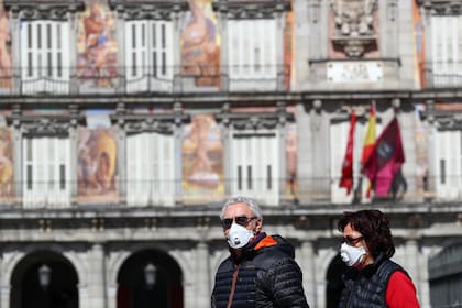 Dos personas caminan con barbijos por la Plaza Mayor de Madrid