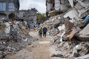 Dos personas caminan entre los escombros de viviendas destruidas por la ofensiva del ejército israelí contra Hamas, en Jabaliya, en el norte de la Franja de Gaza. (AP Foto/Abdel Kareem Hana)
