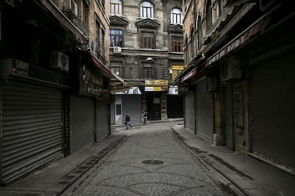 Dos personas caminan por las calles del mercado de Eminonu, en Estambul, una zona usualmente atestada pero ahora casi desierta debido al estricto confinamiento por la pandemia de coronavirus, el sábado 8 de mayo de 2021. (AP Foto/Emrah Gurel)