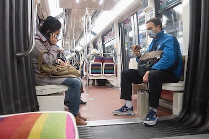 Dos personas con máscaras utilizan sus teléfonos celulares en el Metro de París durante el segundo confinamiento debido a pandemia de coronavirus. París, 17 de noviembre de 2020.