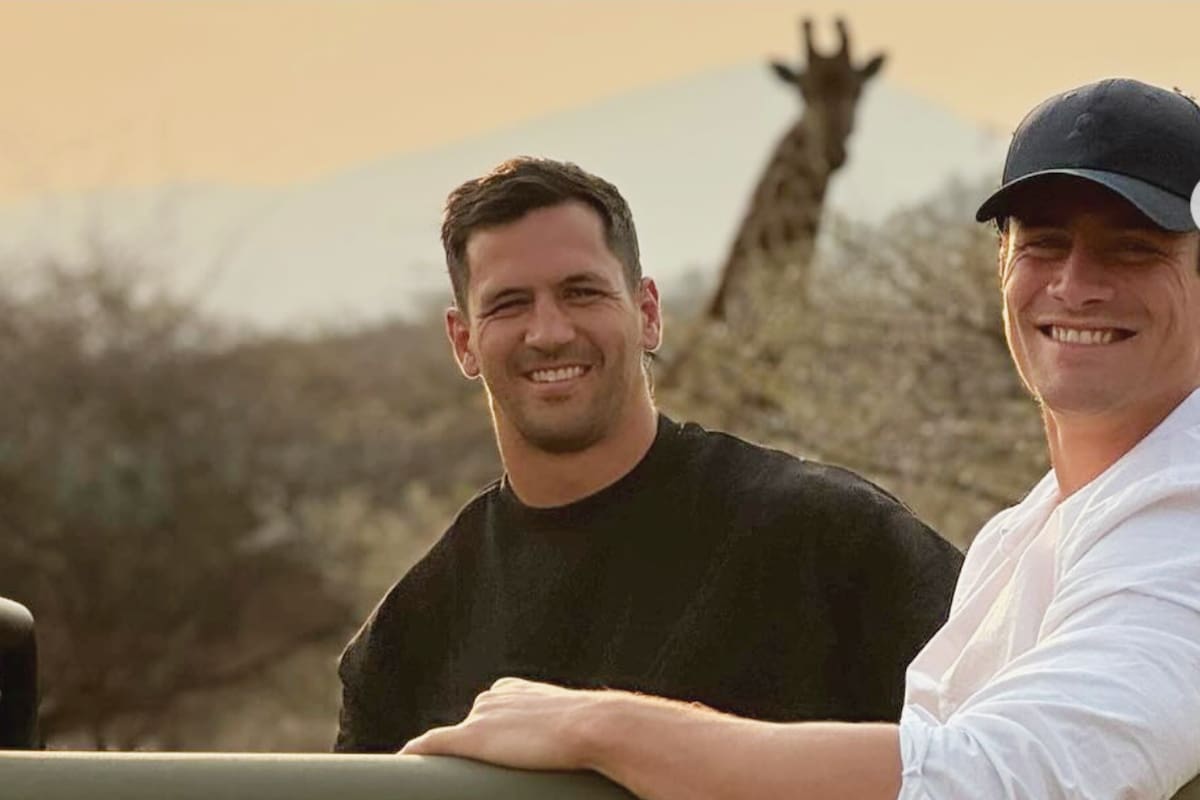 Dos Pumas argentinos y una jirafa sudafricana: Matías Moroni y Bautista Delguy sonríen en el Parque Nacional Kruger delante de un alto y curioso ejemplar autóctono.