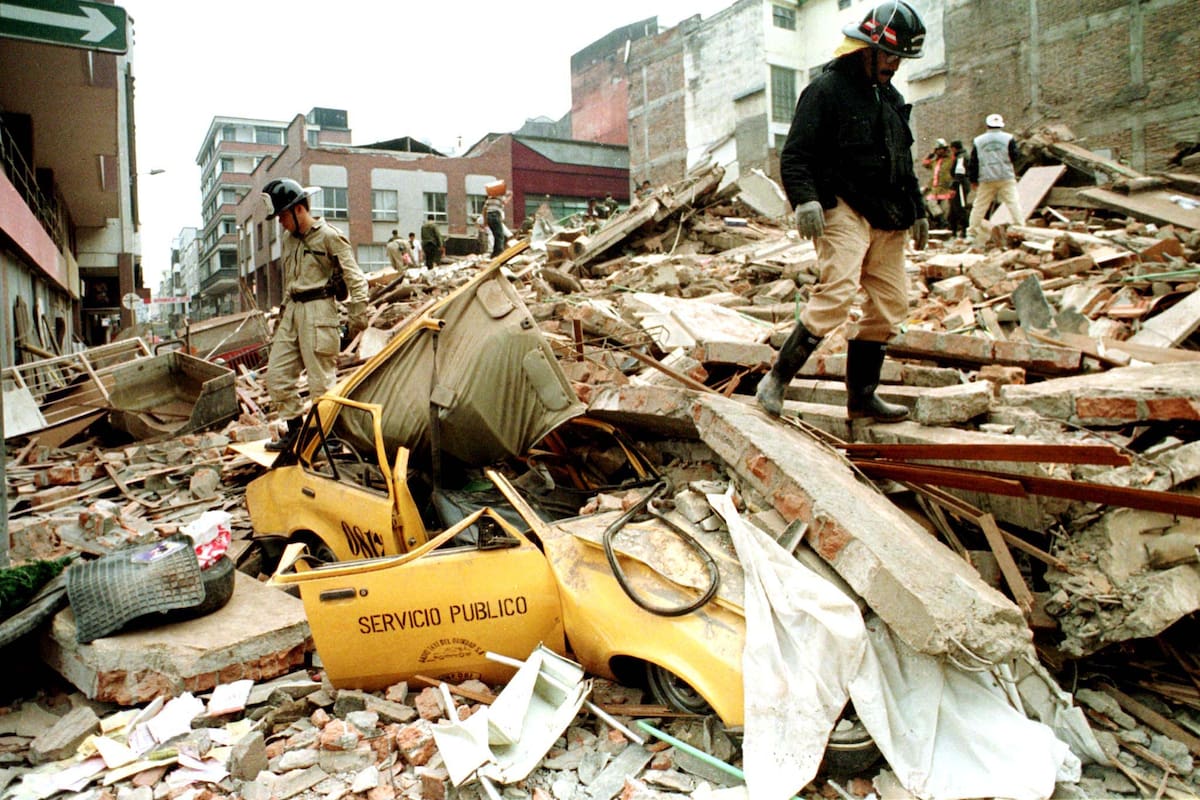 Dos rescatistas caminan sobre los restos de un edificio en Armenia, en enero de 1999