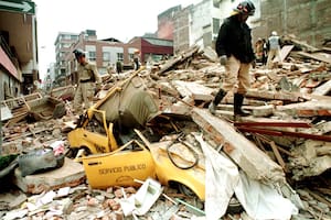 Dos rescatistas caminan sobre los restos de un edificio en Armenia, en enero de 1999